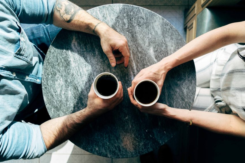 Dwie osoby siedzą przy stoliku nad filiżankami kawy