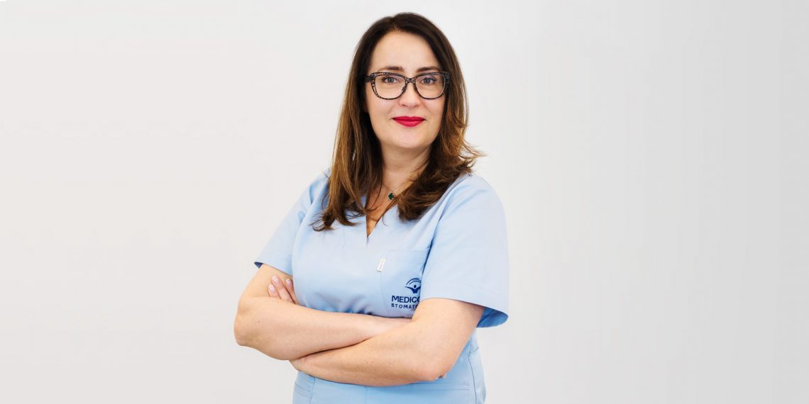 Tekst o wpływie próchnicy na zdrowie serca. Na zdjęciu: Kobieta nosząca okulary i niebieską koszulę - HelloZdrowie
