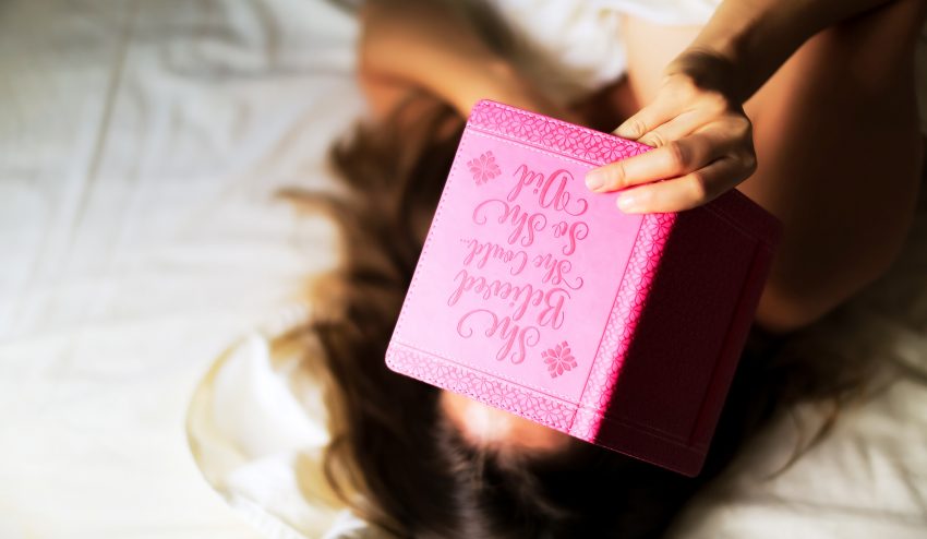 Kobieta leży na łóżku z pamiętnikiem w ręce