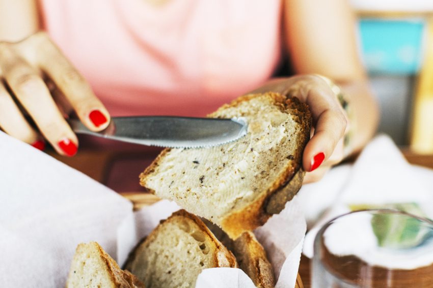 Kobieta smaruje kromkę chleba masłem