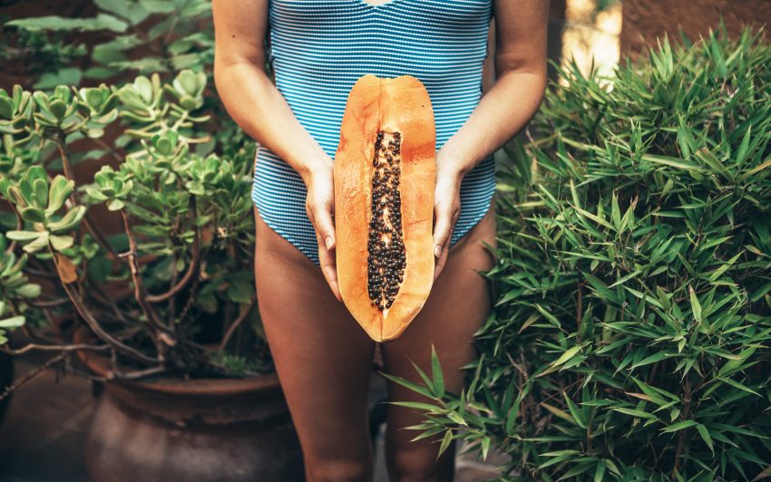 Kobieta w kostiumie kąpielowymm trzyma papaję