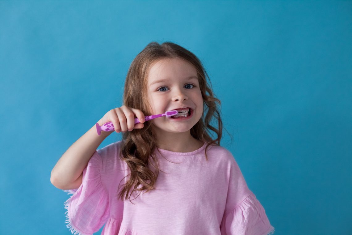 Tekst o higienie jamy ustnej u dzieci. Na zdjęciu: Dziewczyna myjąca zęby - HelloZdrowie