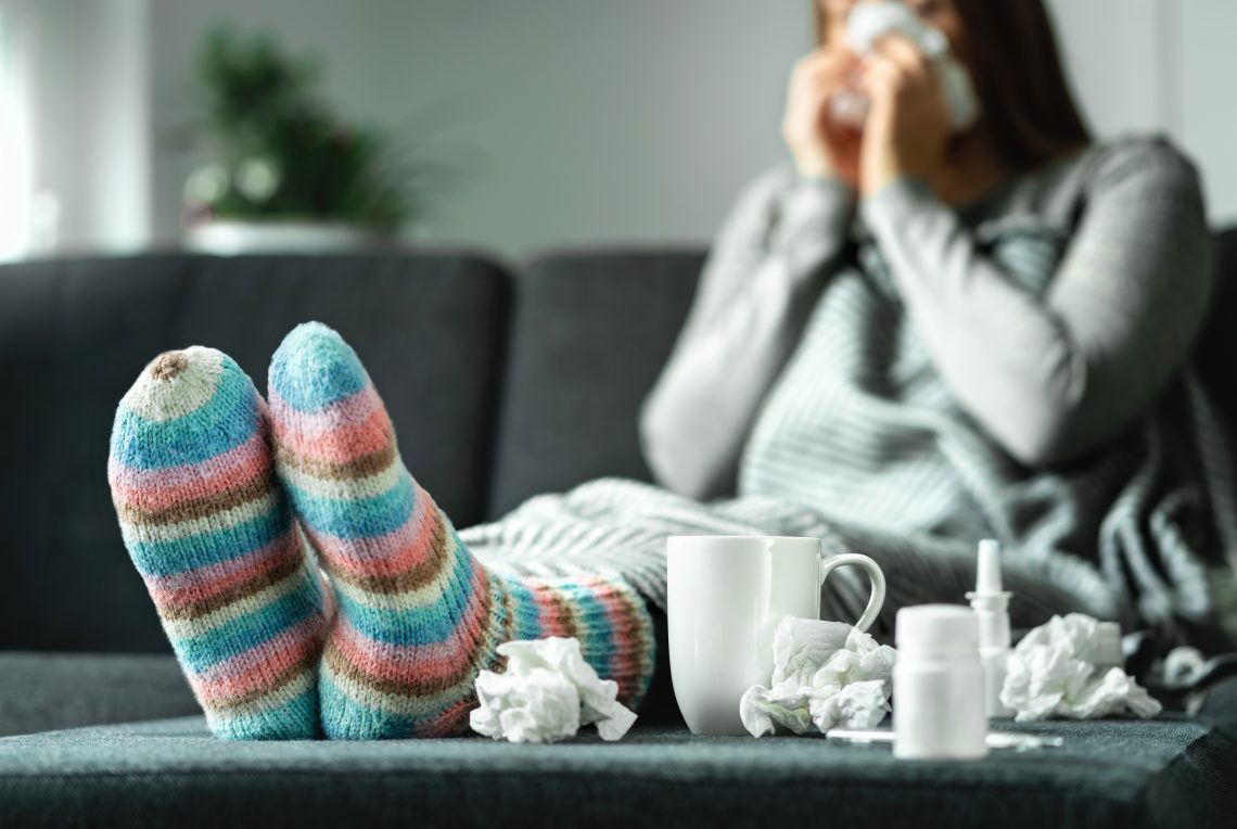 Przeziębiona kobieta siedzi na kanapie