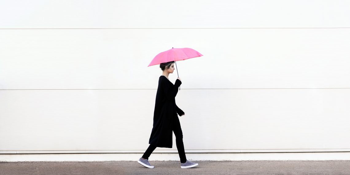 Kobieta idzie z rozłożonym parasolem w ręku