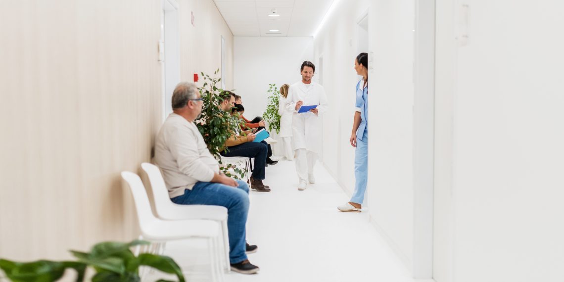 Tekst o awanturujących się pacjentach w kolejce do lekarza. Na zdjęciu: Grupa ludzi w korytarzu - HelloZdrowie
