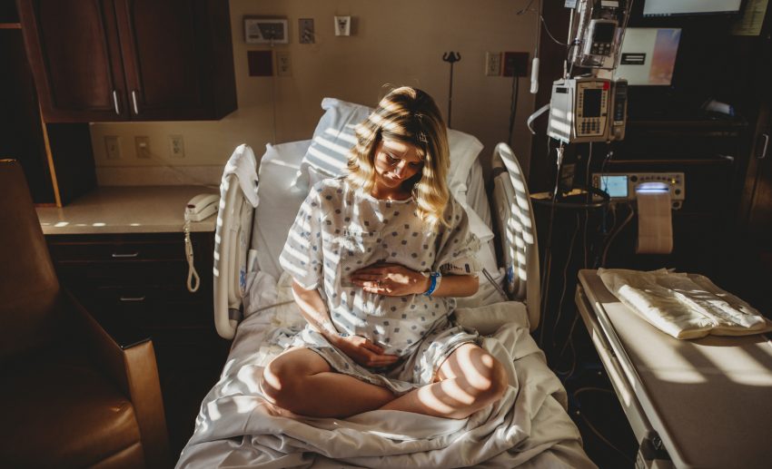 Kobieta w ciazy siedzi na łóżku szpitalnym