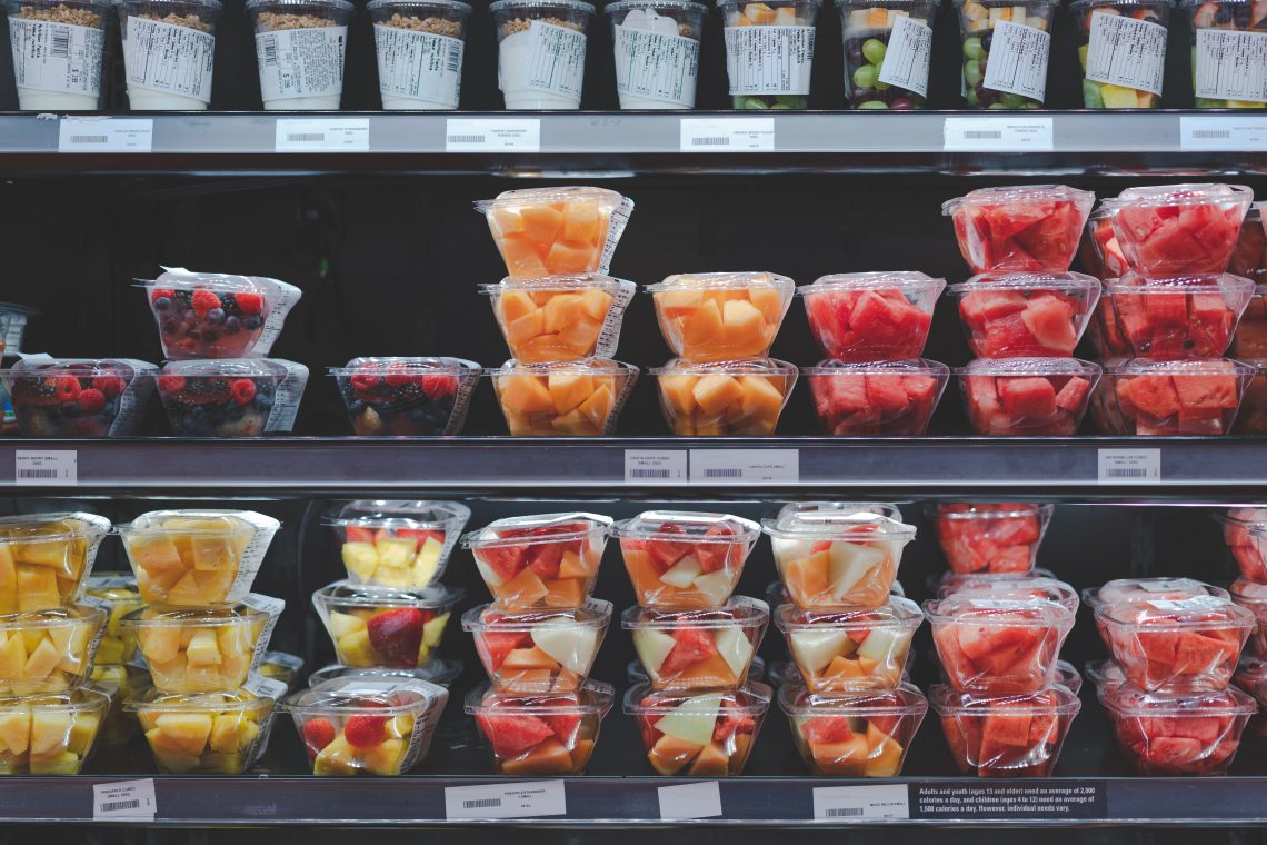 Tekst o dodatkach E w żywności i ich bezpieczeństwie. Na zdjęciu: Półka z plastikowymi pojemnikami owoców - HelloZdrowie