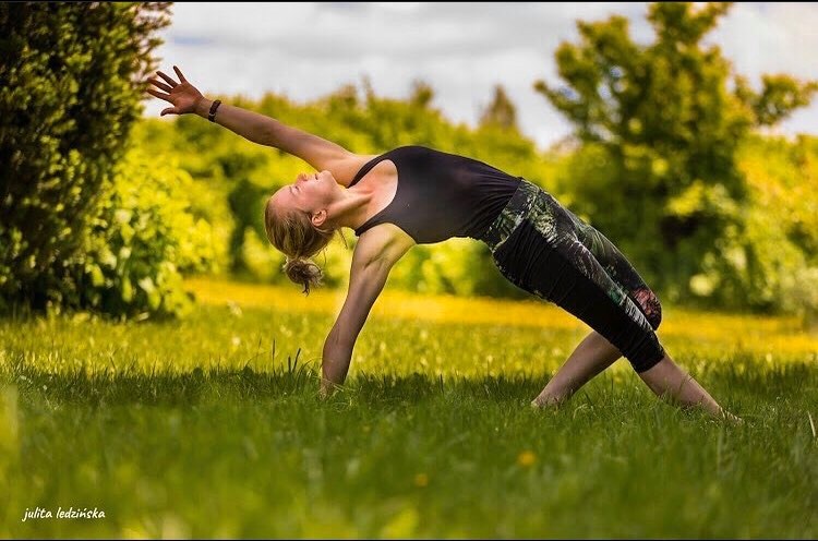 Tekst o drodze i filozofii nauczycielki jogi. Na zdjęciu: Kobieta wykonująca jogę na trawie - HelloZdrowie