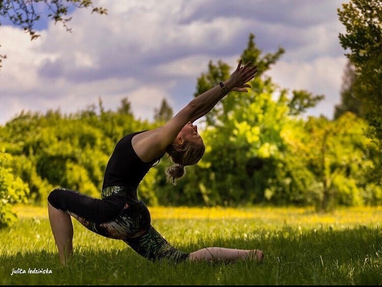 Tekst o drodze i filozofii nauczycielki jogi. Na zdjęciu: Kobieta praktykująca jogę na trawie - HelloZdrowie