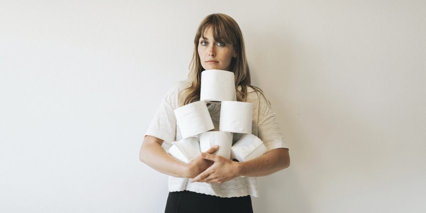 Kobieta trzyma w rękach rolki papieru toaletowego