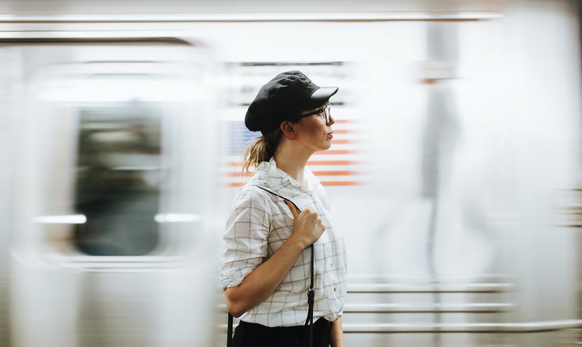 Kobieta w okularach stoi na tle jadącego pociągu