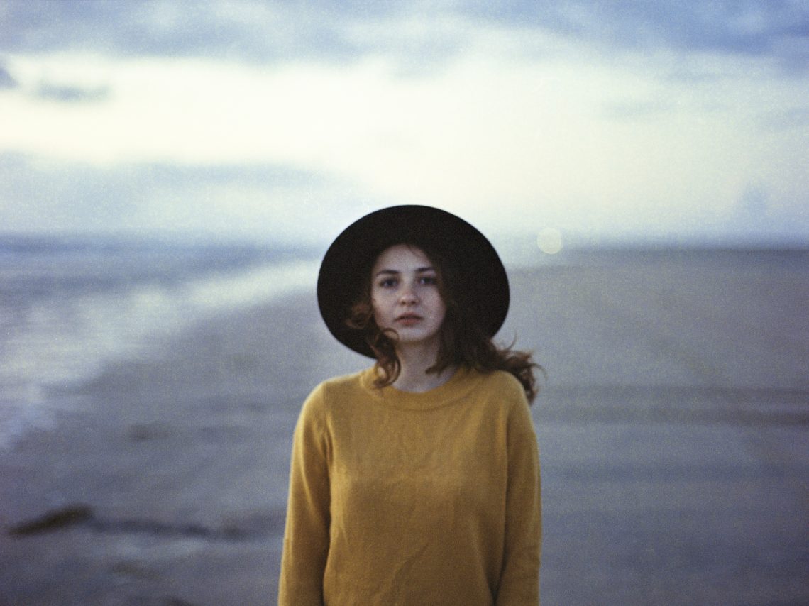 Kobieta na plaży w swetrze i kapeluszu