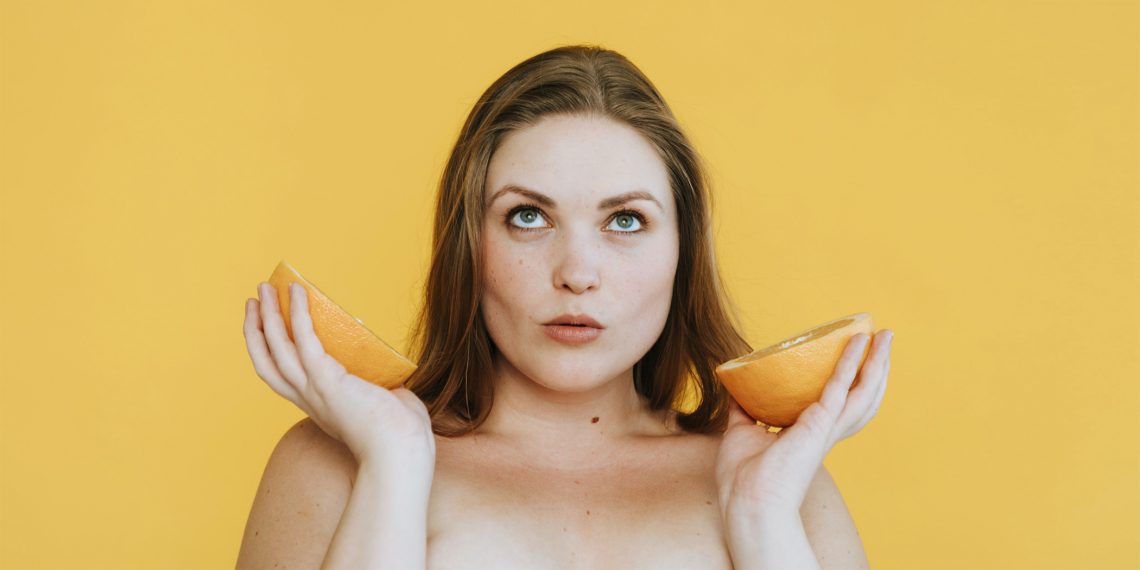 Tekst o hormonalnych przyczynach nadwagi i otyłości. Na zdjęciu: Kobieta trzymająca pomarańcze w swoich rękach - HelloZdrowie