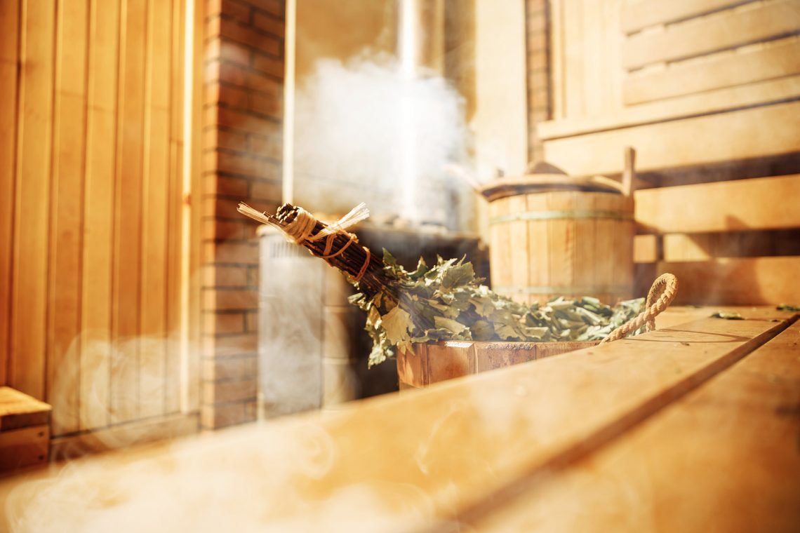 Tekst o korzyściach zdrowotnych regularnego korzystania z sauny. Na zdjęciu: Miotła w saunie - HelloZdrowie