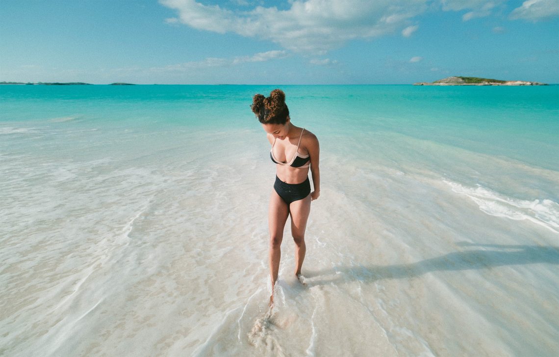 Tekst o używaniu przeterminowanego kremu z filtrem. Na zdjęciu: Kobieta w kostiumie kąpielowym na plaży - HelloZdrowie