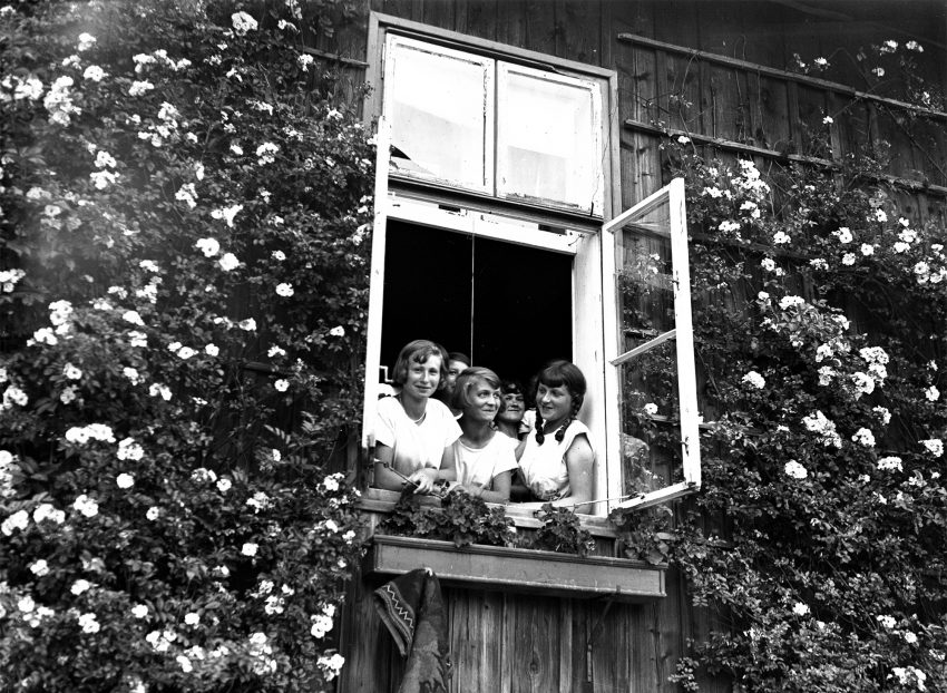 Tekst o historii i zmianach w sanatoriach dziecięcych. Na zdjęciu: Grupa kobiet wpatrujących się przez okno - HelloZdrowie