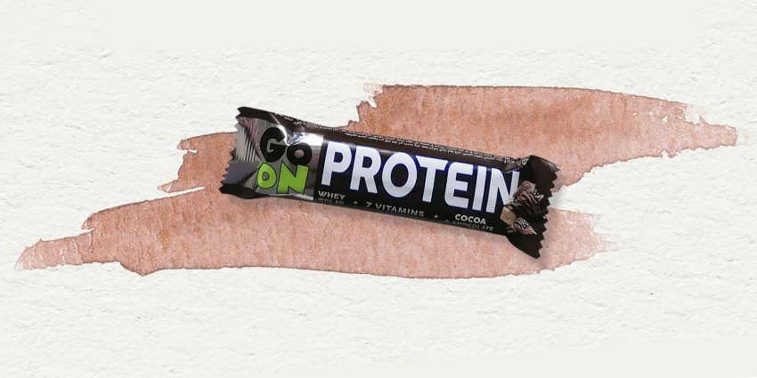 Tekst o batonach proteinowych, ich składzie i korzyściach. Na zdjęciu: Tabliczka czekolady na kawałku papieru - HelloZdrowie