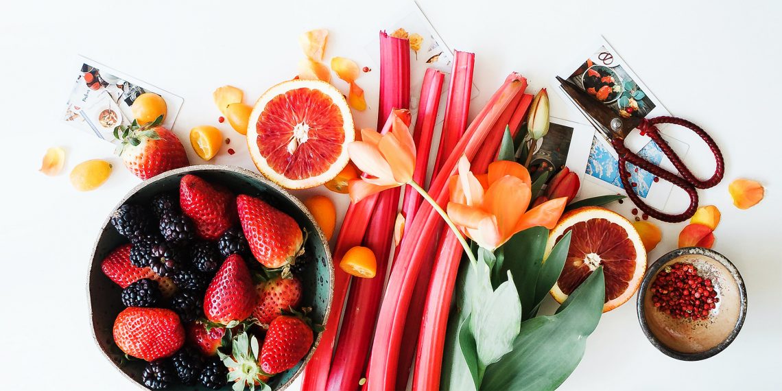 Tekst o sposobach na jedzenie więcej owoców i warzyw. Na zdjęciu: Miska owoców i kwiatów - HelloZdrowie