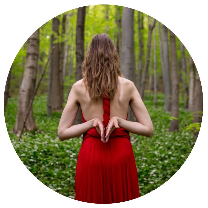 Tekst o korzyściach gimnastyki słowiańskiej dla kobiet. Na zdjęciu: Kobieta w czerwonej sukience w lesie - HelloZdrowie