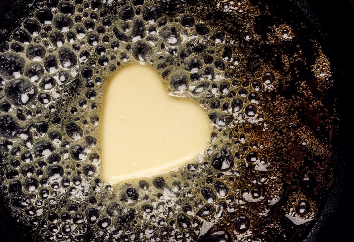 Tekst o wpływie masła i margaryny na cholesterol. Na zdjęciu: Serce kształt masła na patelni - HelloZdrowie