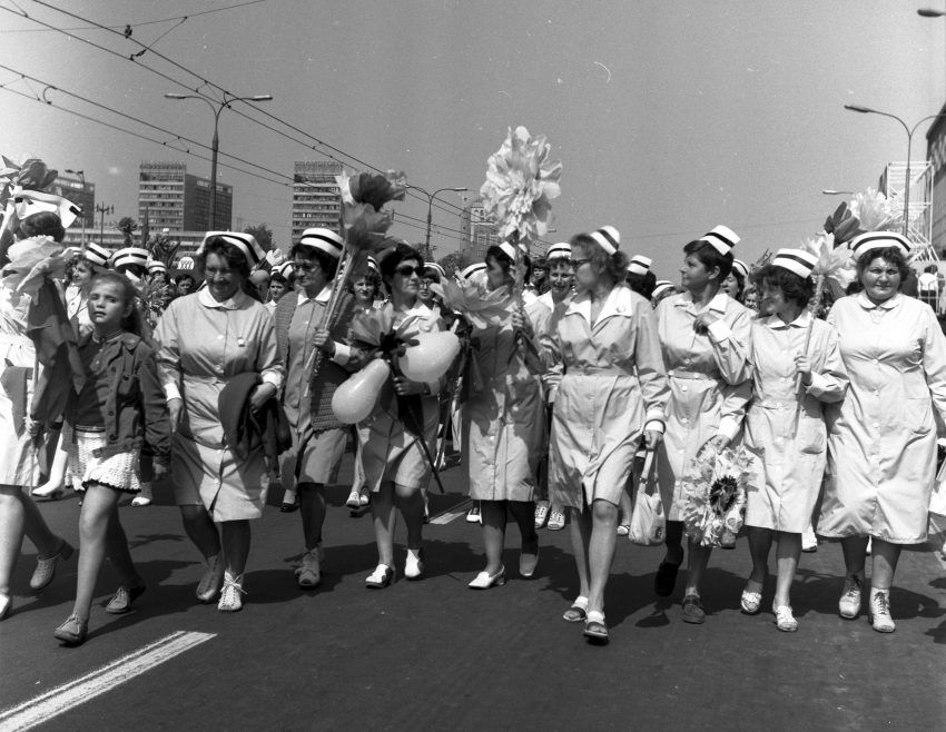 Tekst o ewolucji stroju pielęgniarek na przestrzeni lat. Na zdjęciu: Grupa kobiet w białych sukienkach idąca ulicą - HelloZdrowie