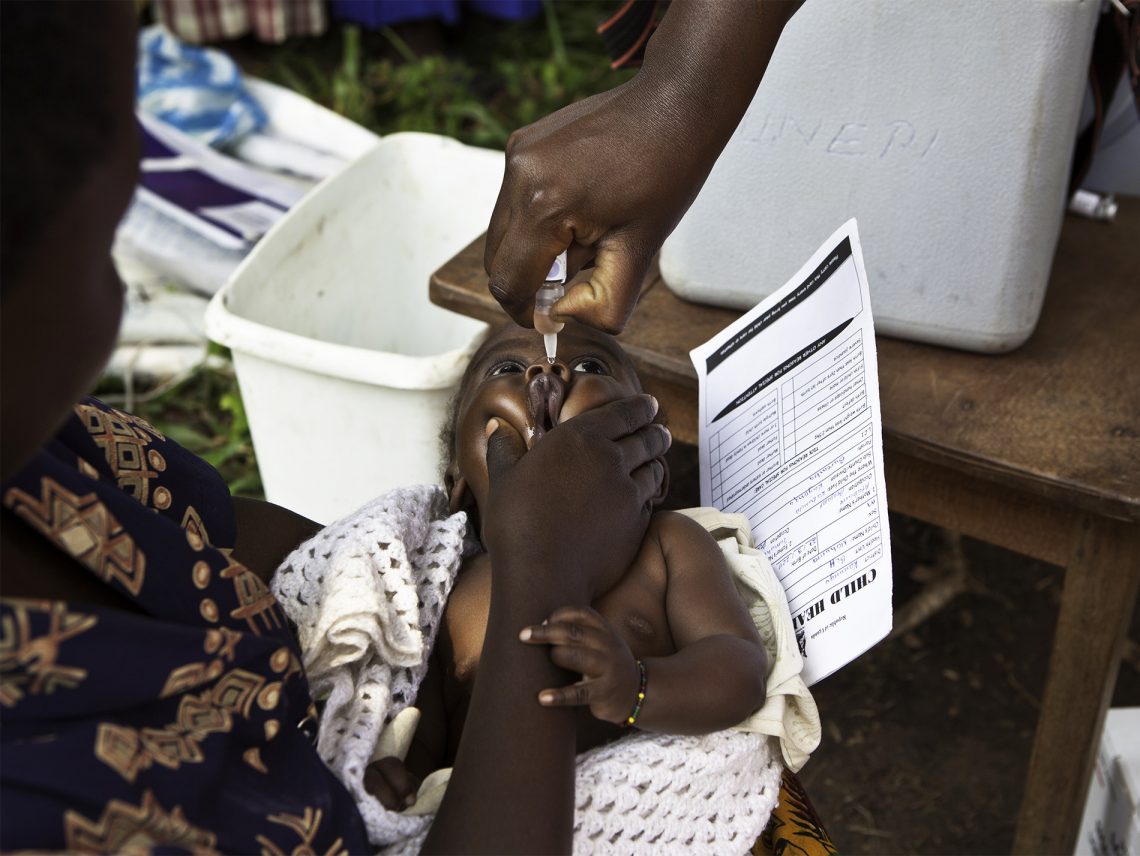 Tekst o Afryce wolnej od polio dzięki szczepieniom. Na zdjęciu: Osoba podająca lekarstwo dziecku - HelloZdrowie