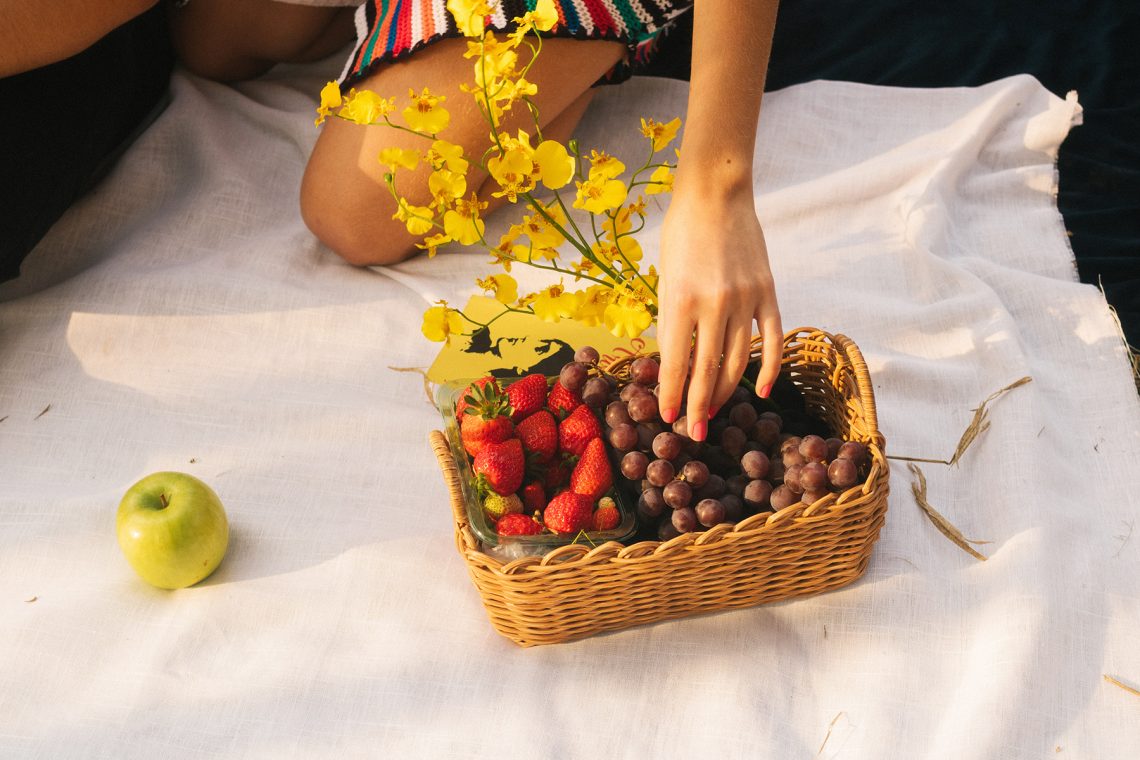 Tekst o filozofii slow food i sposobach wdrożenia. Na zdjęciu: Osoba trzymająca kosz z owocami - HelloZdrowie