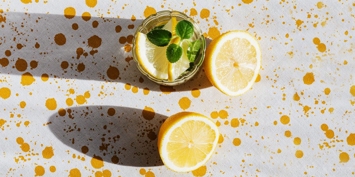 Tekst o zdrowotnych zaletach jedzenia cytrusów. Na zdjęciu: Pół przekrojonego limonki i szklanka wody - HelloZdrowie