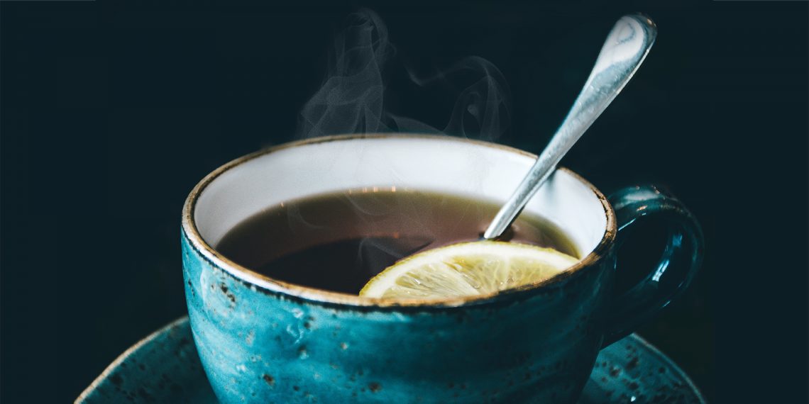 Kubek z herbatą, cytryną i łyżeczką
