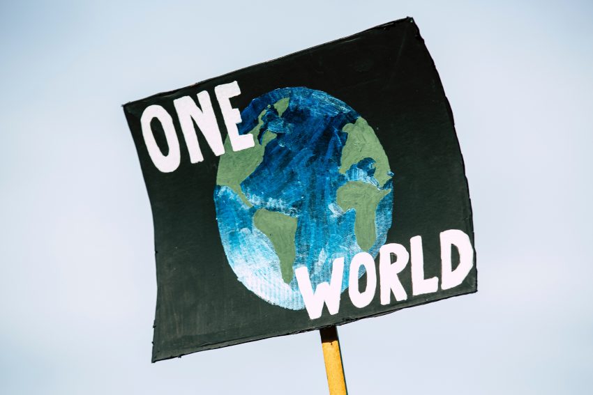 Plakat a na nim narysowana kula ziemska i napis "One world" (jeden świat)