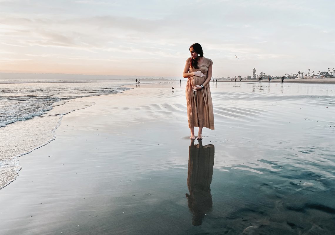 Tekst o ryzyku i profilaktyce zawału w ciąży. Na zdjęciu: Kobieta stojąca na plaży - HelloZdrowie