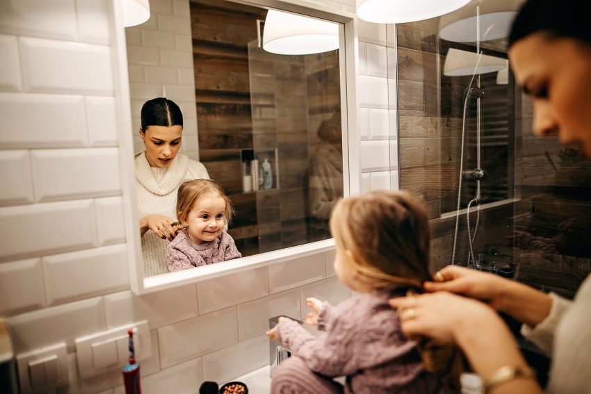 Kobieta czesze córkę przed lustrem