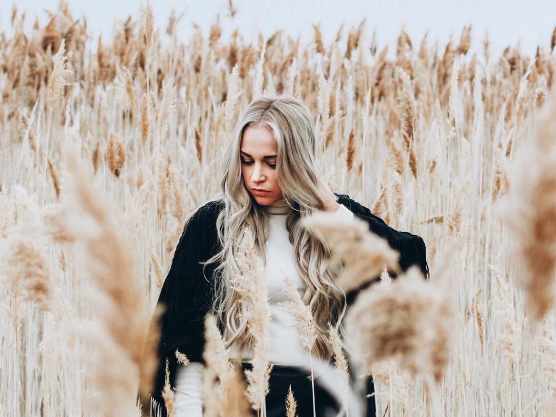 Tekst o chorobach nadnerczy, objawach i leczeniu. Na zdjęciu: Kobieta stojąca na polu wysokiej trawy - HelloZdrowie