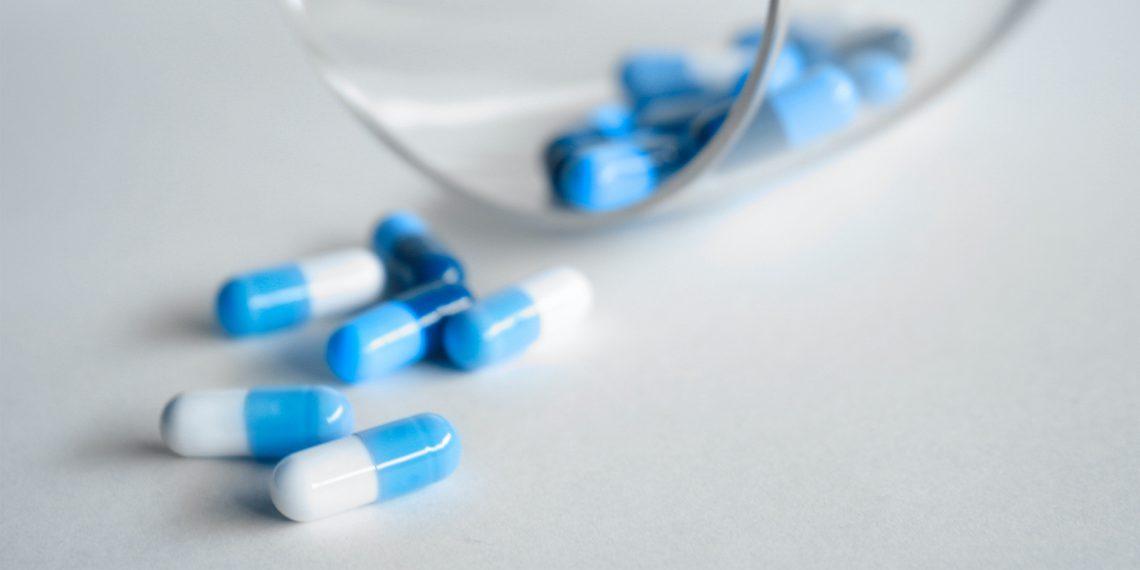 Tekst o skuteczności leków przeciwhistaminowych w leczeniu COVID-19. Na zdjęciu: Zbliżenie niebieskich i białych tabletek - HelloZdrowie