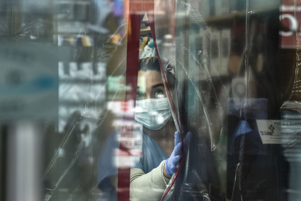 Tekst o zagrożeniu epidemii wirusa Nipah. Na zdjęciu: Osoba w masce i rękawiczkach spoglądająca przez okno - HelloZdrowie