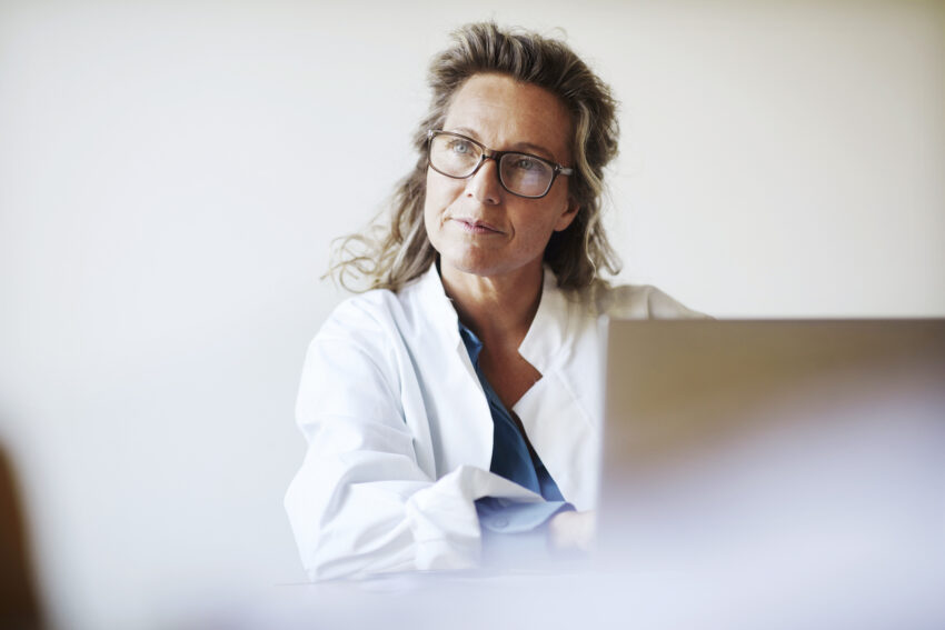 na zdjęciu: lekarka siedząca przy biurku patrzy wyczekująco na pacjenta, tekst o pytaniu, na które pacjenci najczęściej nie znają odpowiedzi /fot. Getty Images