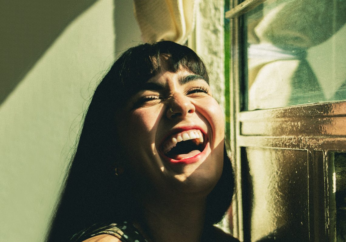 Tekst o budowie, funkcjach i chorobach jamy ustnej. Na zdjęciu: Kobieta śmiejąca się przed oknem - HelloZdrowie