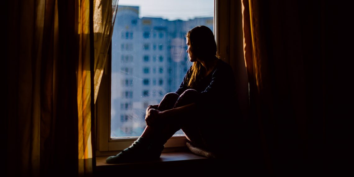 Tekst o wenlafaksynie: działanie, skutki uboczne, odstawienie. Na zdjęciu: Kobieta siedząca na parapetem okna - HelloZdrowie