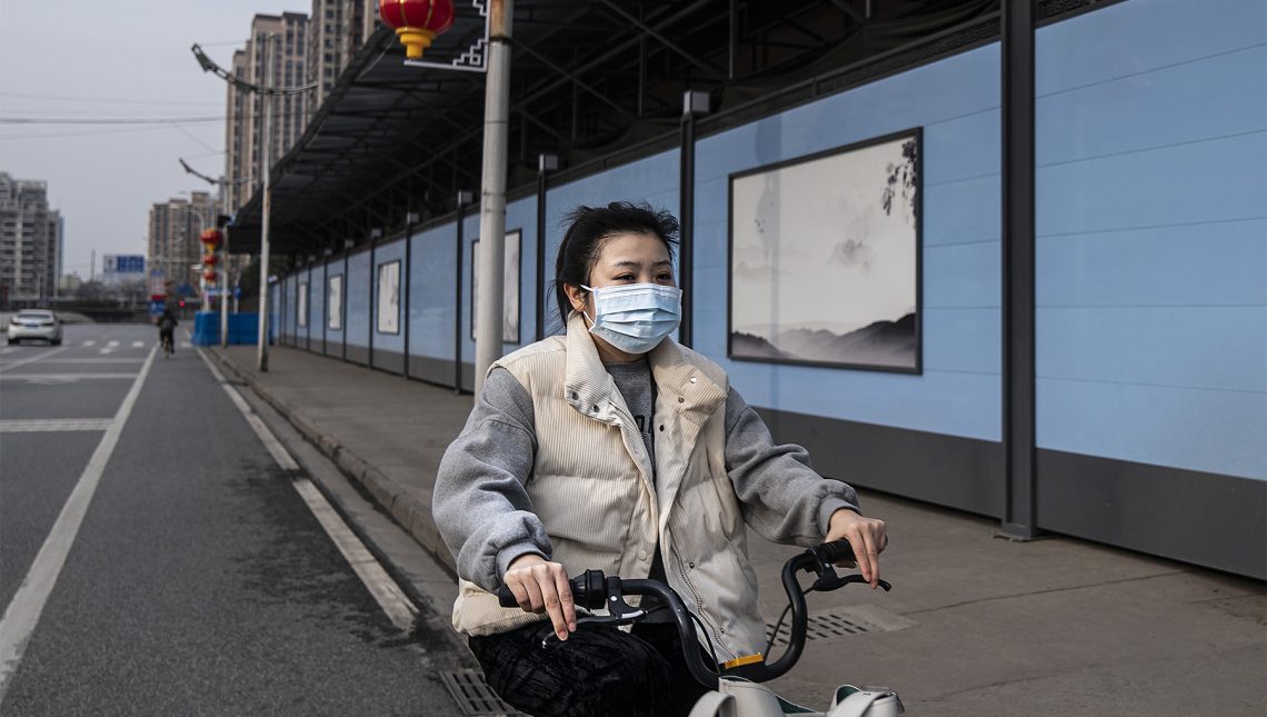 Tekst o wcześniejszych ostrzeżeniach przed targiem w Wuhan. Na zdjęciu: Kobieta w masce na twarz na rowerze - HelloZdrowie