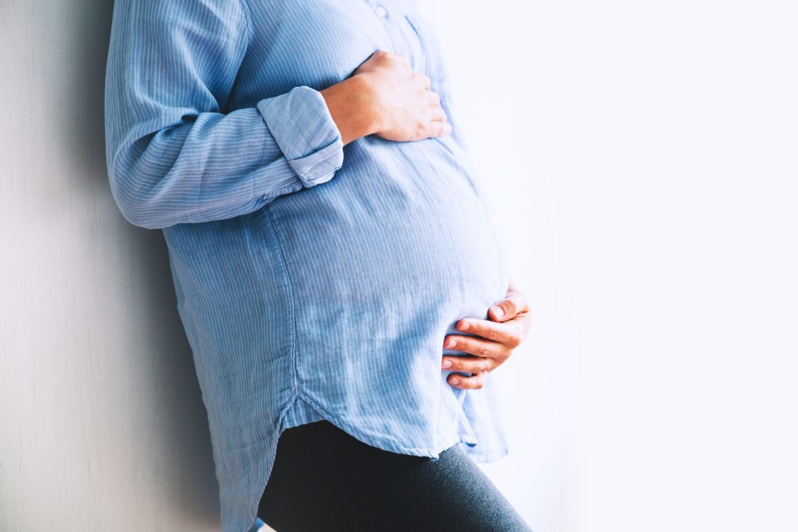Tekst o leczeniu COVID-19 u kobiet w ciąży. Na zdjęciu: Kobieta w ciąży trzymająca brzuch - HelloZdrowie
