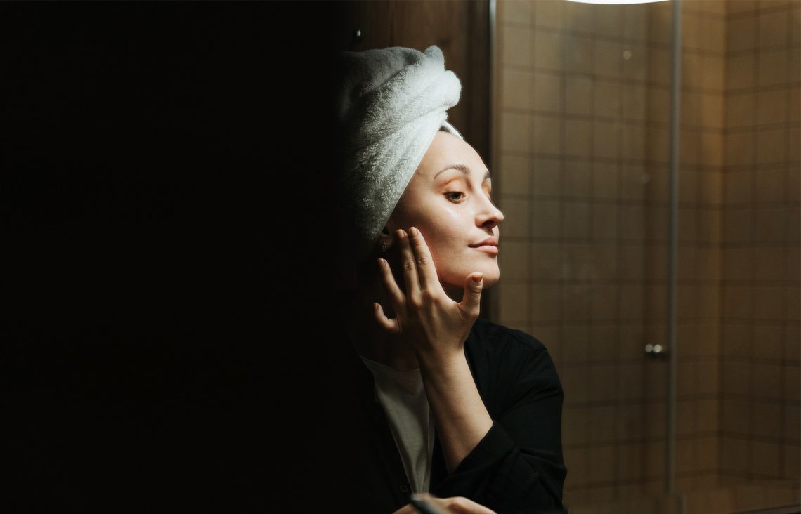 Tekst o metodzie oczyszczania twarzy olejami OCM. Na zdjęciu: Kobieta z ręcznikiem na głowie - HelloZdrowie
