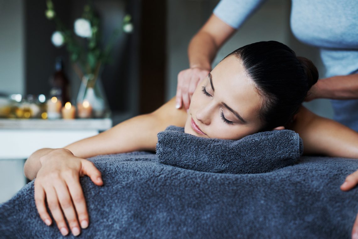 Tekst o korzyściach i technikach masażu limfatycznego. Na zdjęciu: Kobieta leżąca na ręczniku z zamkniętymi oczami - HelloZdrowie