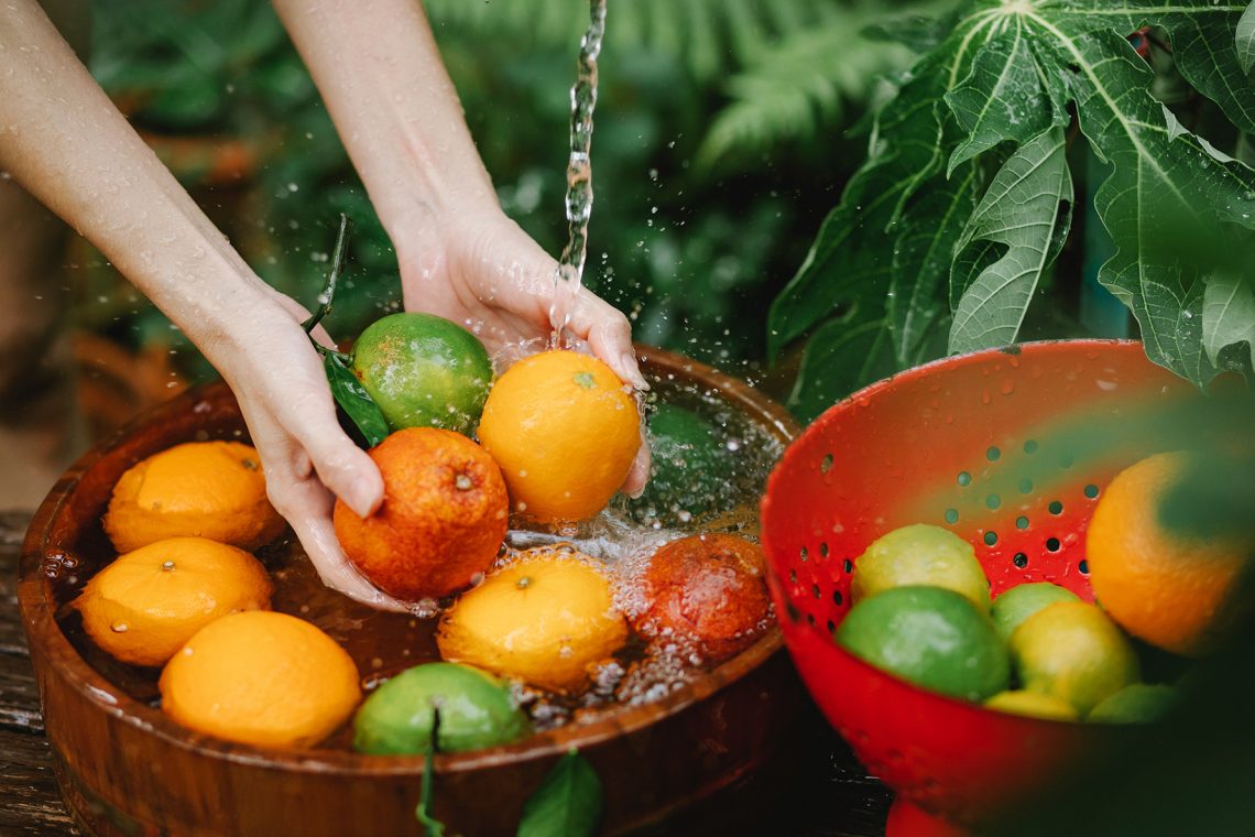 Tekst o objawach, diagnostyce i profilaktyce WZW typu E. Na zdjęciu: Osoba myjąca pomarańcze w misce z wodą - HelloZdrowie
