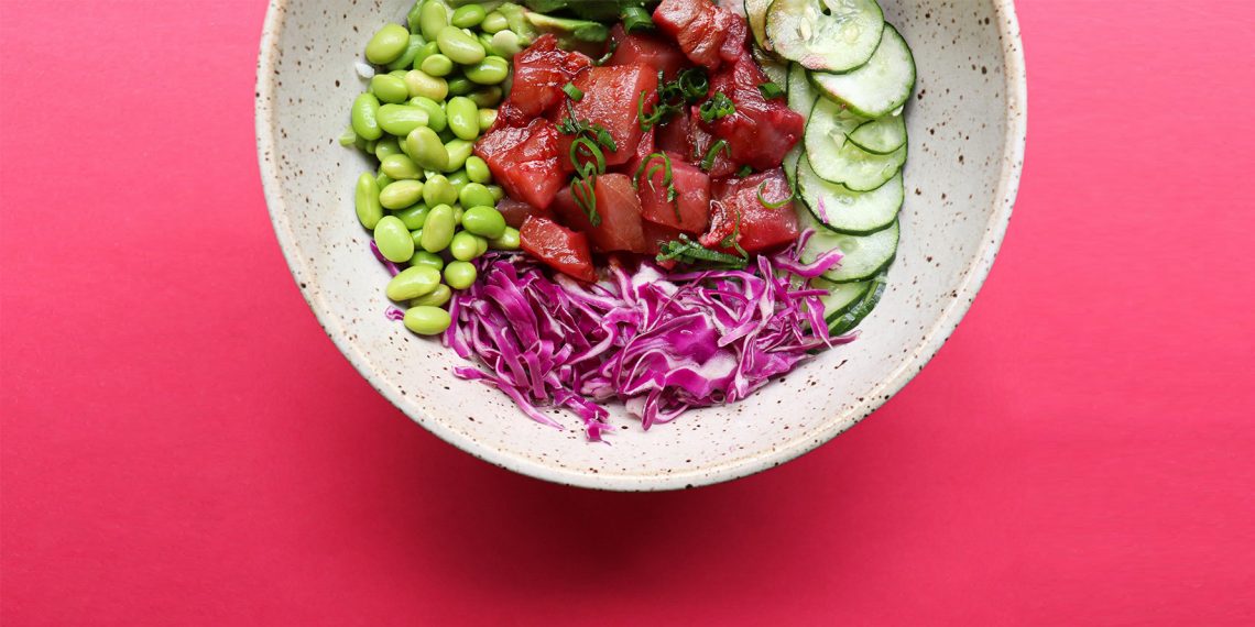 Tekst o zdrowotnych aspektach tuńczyka i przepisach kulinarnych. Na zdjęciu: Miska jedzenia na czerwonym tle - HelloZdrowie