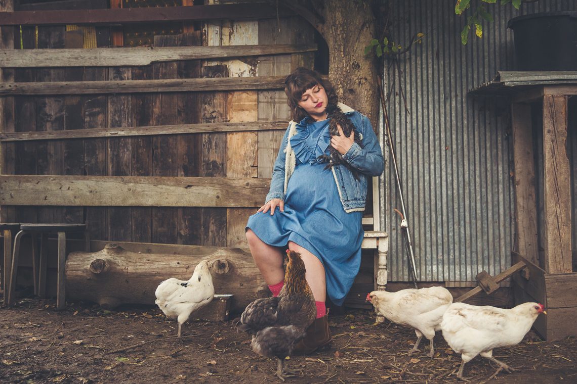 Tekst o codziennym życiu matki wielodzietnej na wsi. Na zdjęciu: Kobieta w niebieskiej sukience z kurami - HelloZdrowie