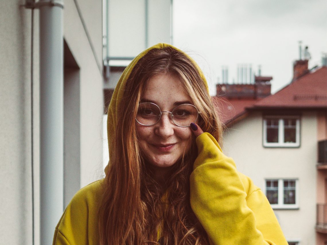 Tekst o walce z depresją i próbach samobójczych. Na zdjęciu: Kobieta, która nosi okulary i żółtą bluzę z kapturem - HelloZdrowie