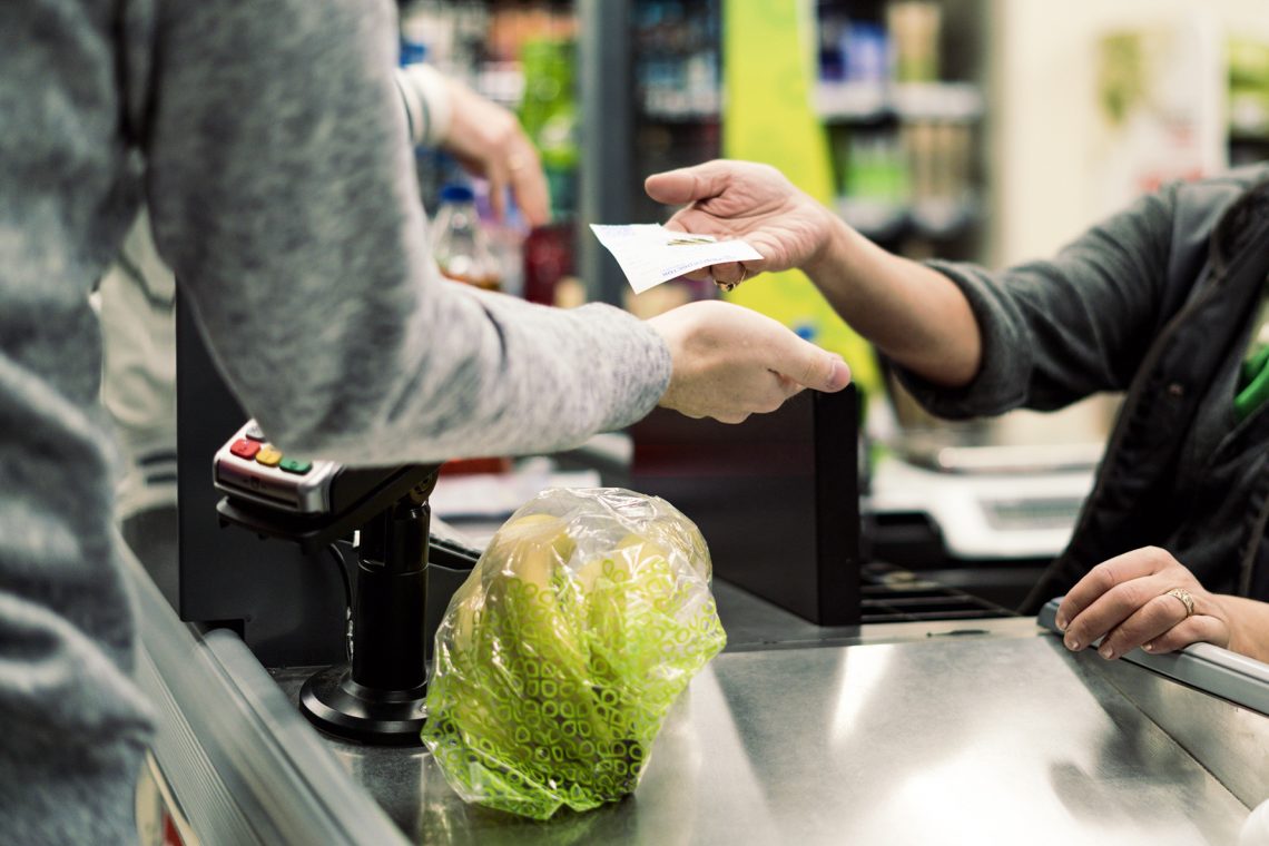 Tekst o niebieskich paragonach i ich recyklingu. Na zdjęciu: Osoba płacąca u kasjera - HelloZdrowie