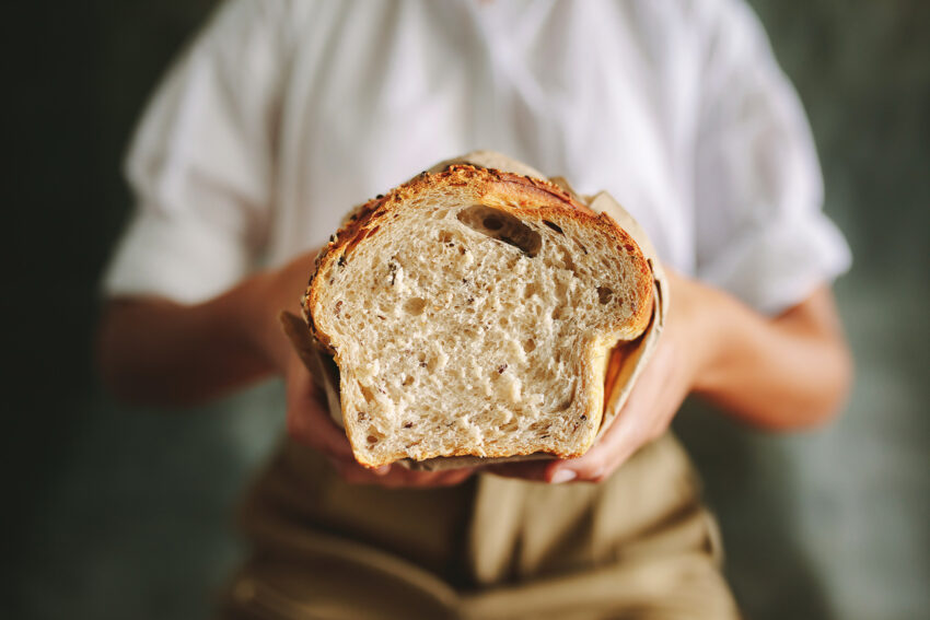 Kobieta trzyma w dłoniach bochenek chleba