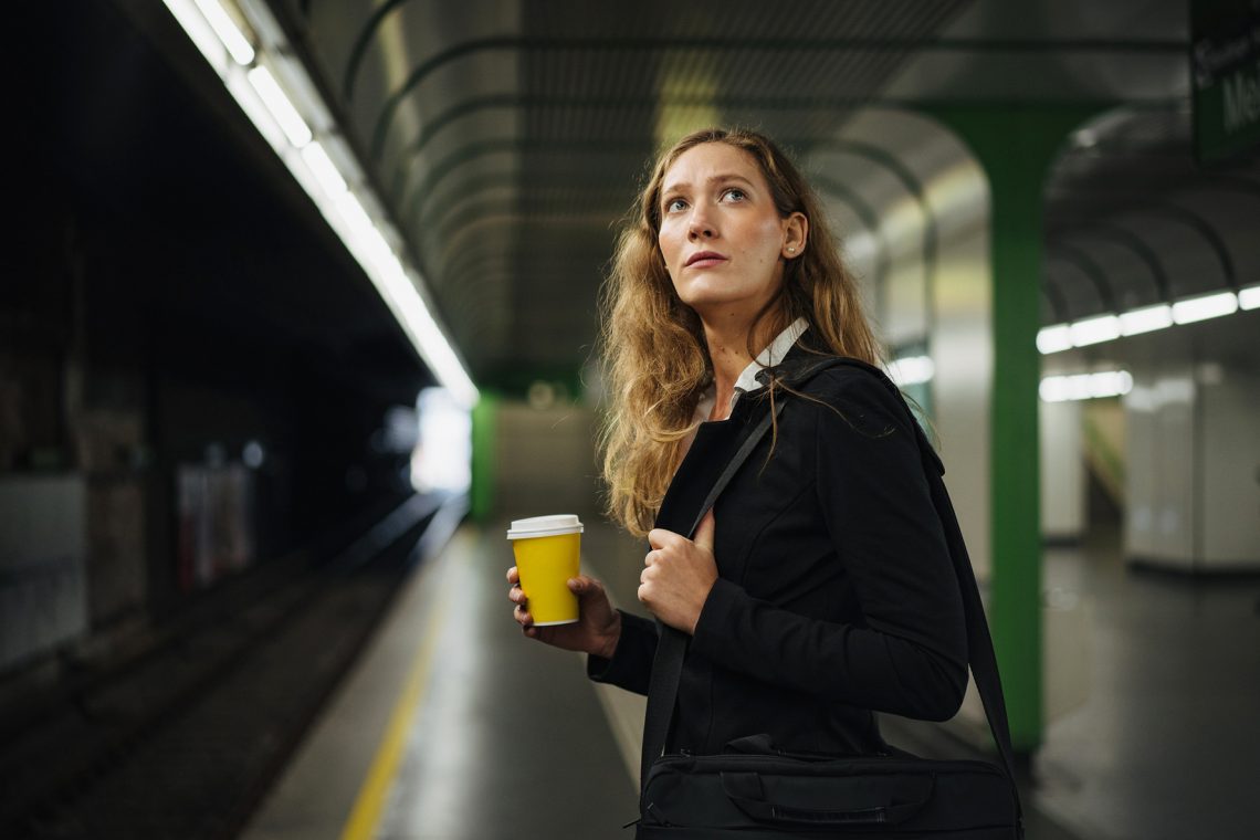 Kobieta czeka na metro. W ręce trzyma kubek