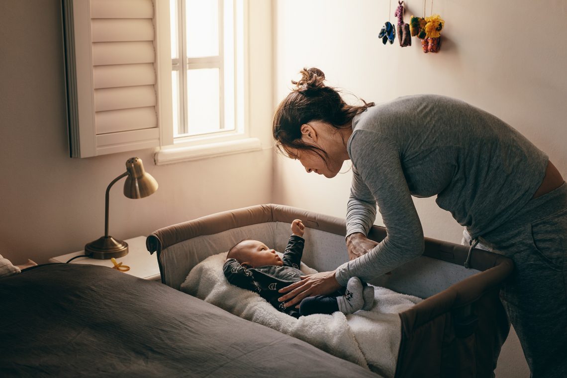 Kobieta kładzie niemowlę do łóżeczka
